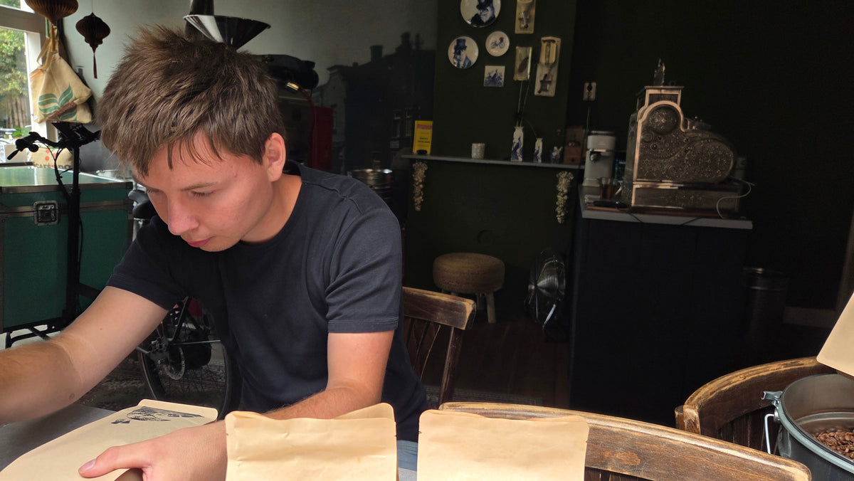 Piet plakt etiketten op verpakkingen bij TAS Specialty Coffee